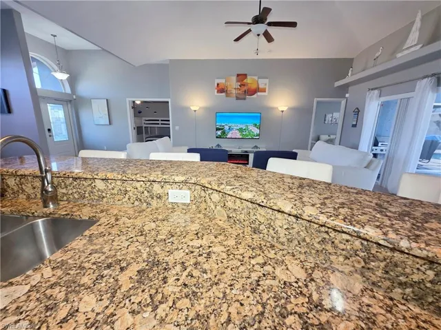 Kitchen featuring light stone countertops, open floor plan, ceiling fan, and pendant lighting