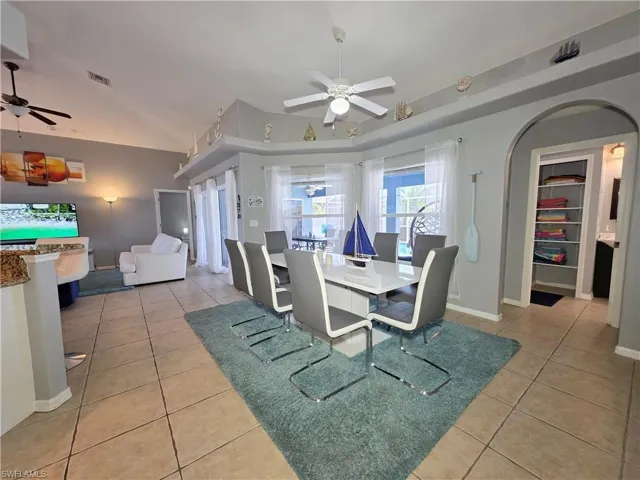 Dining room with ceiling fan, light tile patterned flooring, and arched walkways