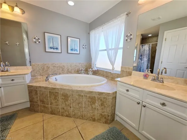Full bathroom with two vanities, light tile patterned floors, a garden tub, a shower with curtain, and recessed lighting