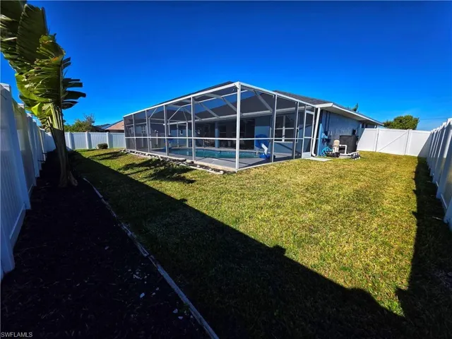Rear view of property featuring a fenced backyard, a sunroom, glass enclosure, and stucco siding