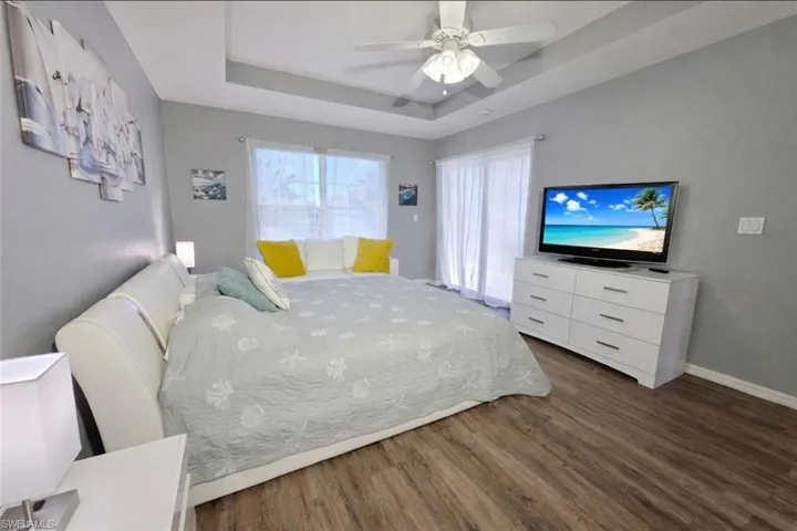 Bedroom featuring a raised ceiling, a ceiling fan, and wood finished floors