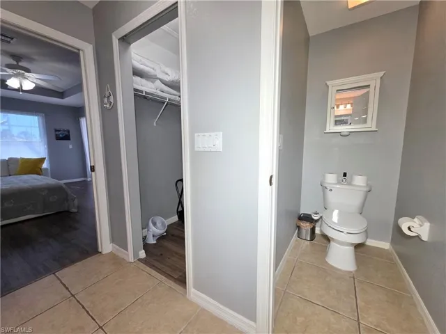 Bathroom with light tile patterned floors, ceiling fan, ensuite bathroom, and a walk in closet