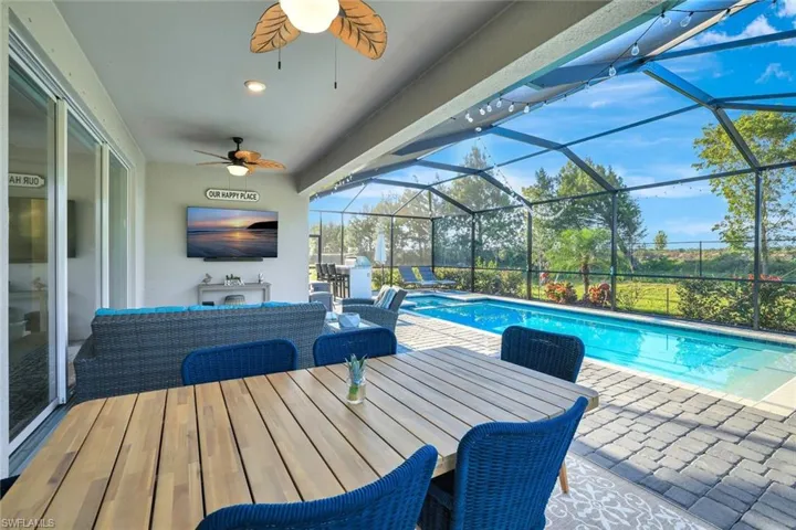 View of pool featuring a patio area, a ceiling fan, an outdoor hangout area, and glass enclosure