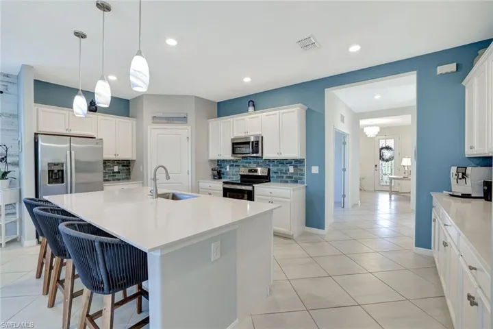 Kitchen with stainless steel appliances, light tile patterned floors, a sink, and decorative backsplash