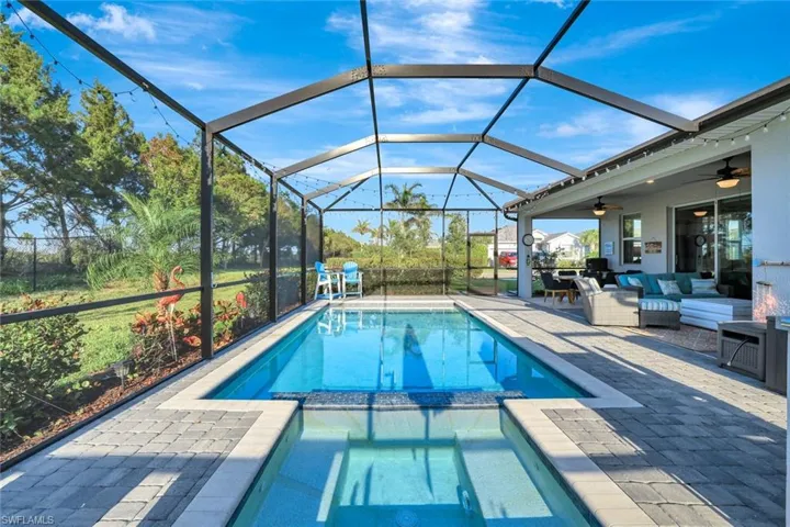 View of swimming pool featuring ceiling fan, a pool with connected hot tub, an outdoor living space, glass enclosure, and a patio
