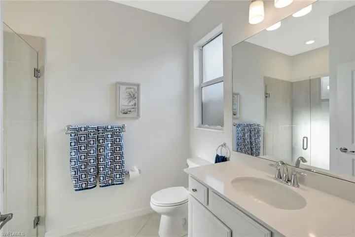 Full bathroom featuring toilet, a stall shower, baseboards, and tile patterned flooring