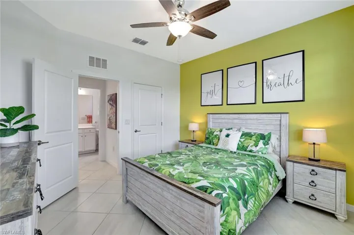 Bedroom with light tile patterned floors, visible vents, baseboards, and ceiling fan