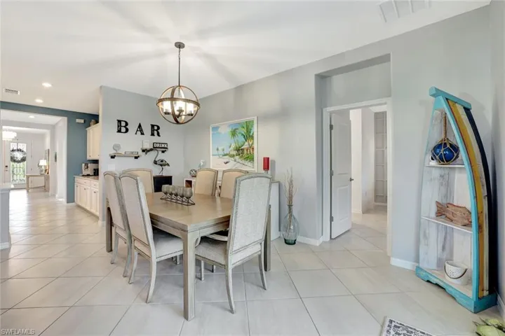 Dining area with light tile patterned floors, visible vents, baseboards, and an inviting chandelier
