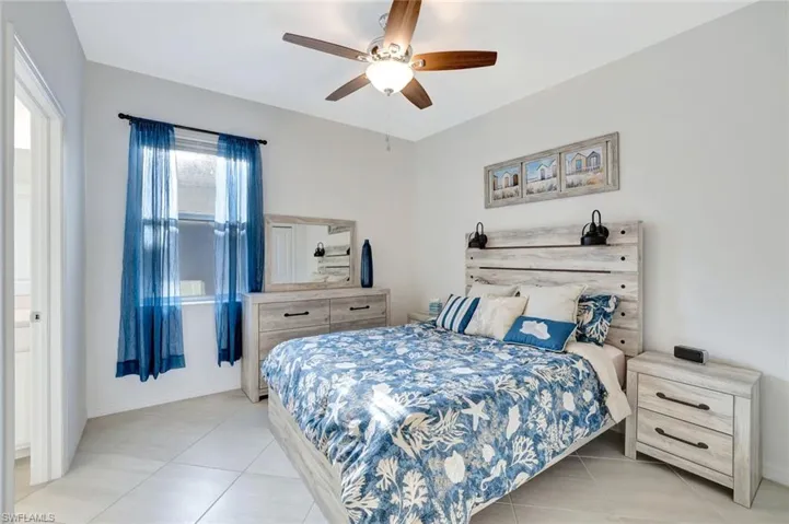 Bedroom with light tile patterned floors, baseboards, and a ceiling fan