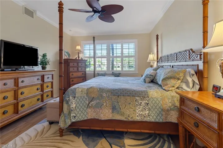 Bedroom with visible vents, crown molding, wood finished floors, and a ceiling fan