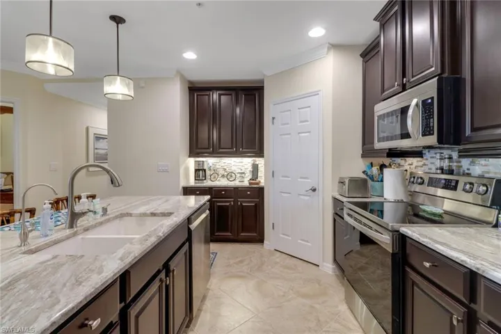 Kitchen with backsplash, ornamental molding, a sink, and stainless steel appliances