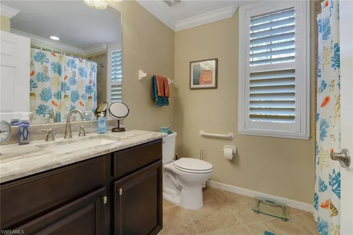 Bathroom featuring tile patterned flooring, vanity, crown molding, toilet, and baseboards