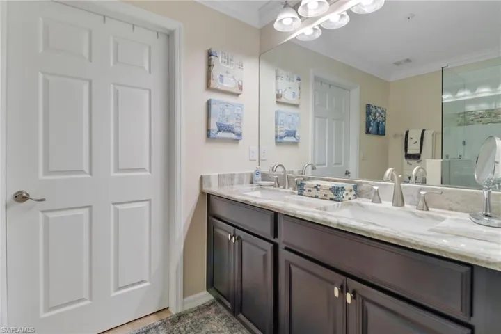 Full bathroom with double vanity, a sink, and crown molding