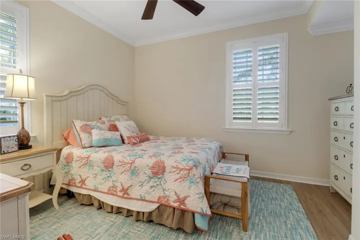 Bedroom featuring baseboards, crown molding, multiple windows, and wood finished floors