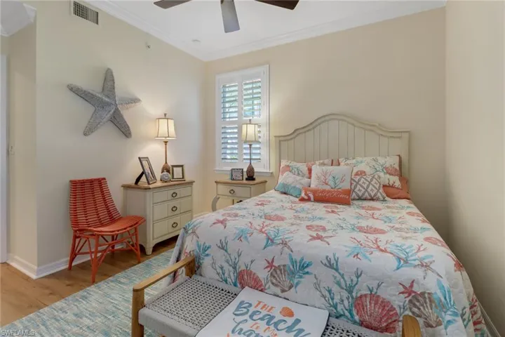 Bedroom featuring visible vents, baseboards, ornamental molding, ceiling fan, and wood finished floors
