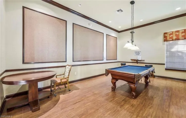 Recreation room with wood finished floors, crown molding, baseboards, and visible vents