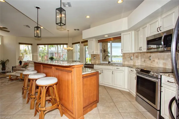 Kitchen with custom cabinetry, stainless steel appliances, light stone countertops, and a healthy amount of sunlight