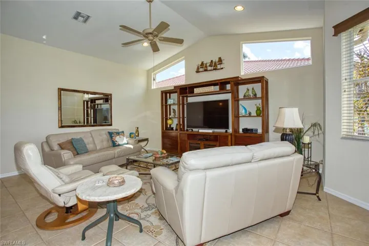 Living room featuring high vaulted ceiling, tile patterned floors, and a wealth of natural light