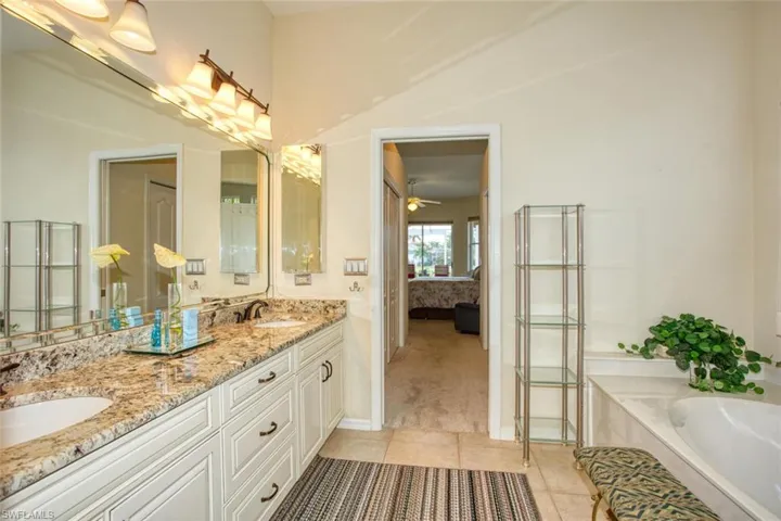 Bathroom with vanity, ceiling fan, a tub, and tile floors