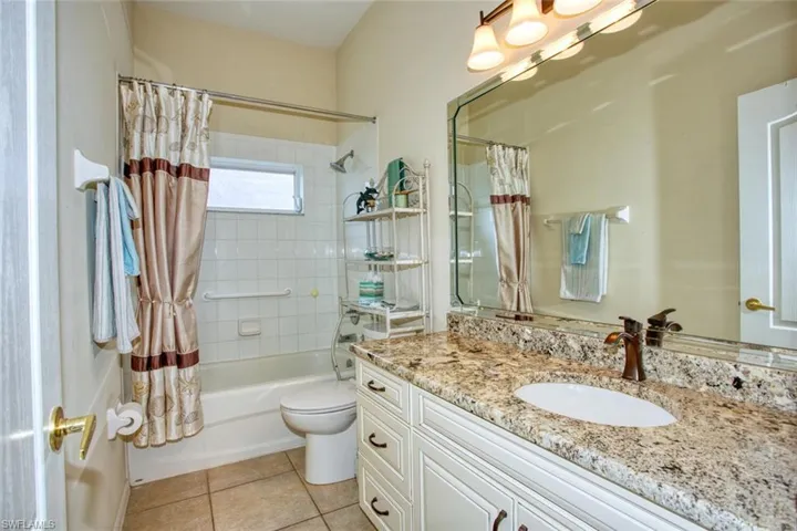 Full bathroom featuring vanity, shower / bath combination with curtain, toilet, and tile patterned flooring