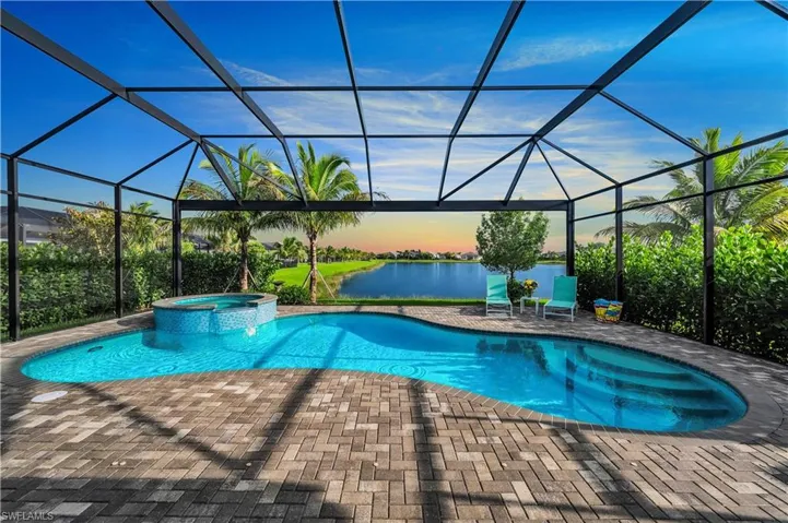 Pool at dusk featuring screened enclosure, a lake view and breathtaking sunsets