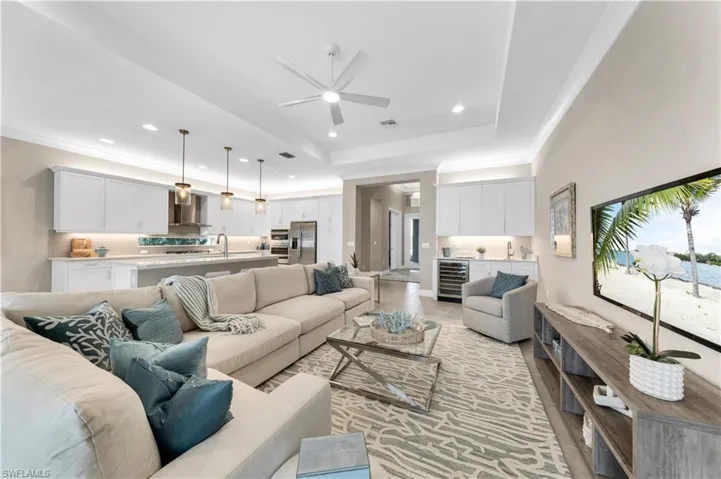 Living room featuring ceiling fan, a tray ceiling, beverage cooler, and sink