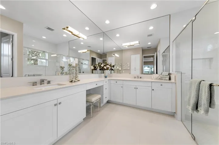 Bathroom featuring double sink vanity, walk in shower, and tile patterned floors