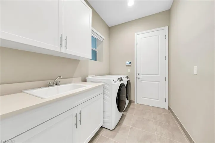 Washroom with cabinets, light tile patterned flooring, sink, and independent washer and dryer