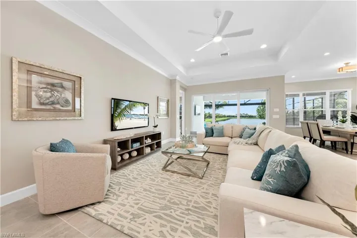 Living room with ceiling fan, a tray ceiling, and light tile patterned floors