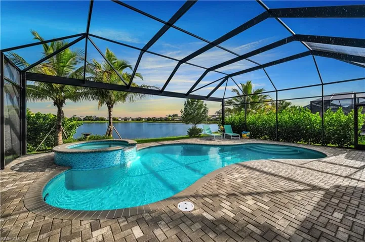 Pool at dusk featuring an in ground hot tub, a lanai, and a patio