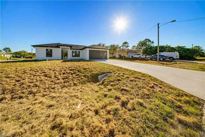 Prairie-style home featuring concrete driveway, stucco siding, a front yard, and an attached garage
