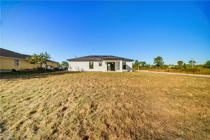 Rear view of house with a lawn and stucco siding