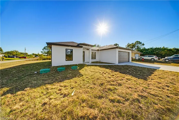 View of front of house with a front lawn, driveway, stucco siding, and a garage