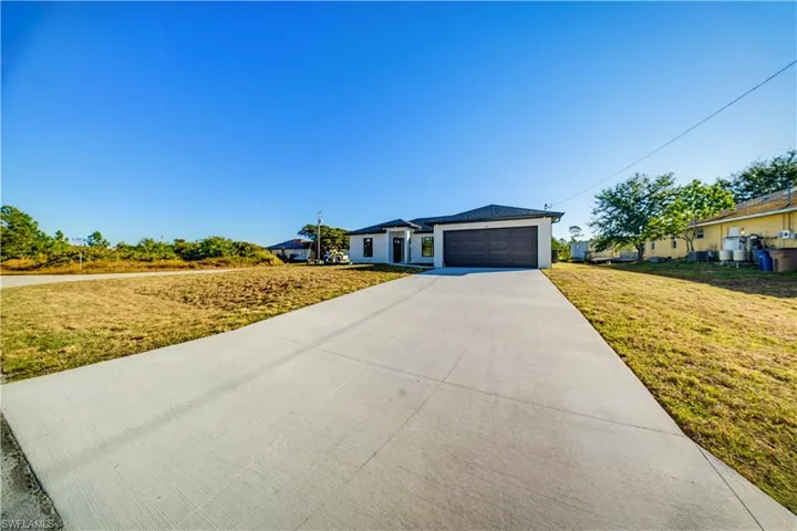 View of front of house with a front yard, concrete driveway, and an attached garage