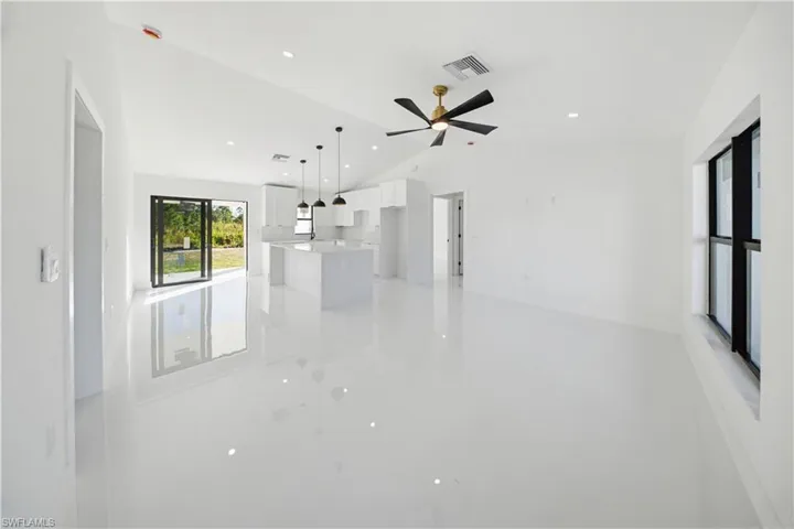 Unfurnished living room with lofted ceiling and recessed lighting