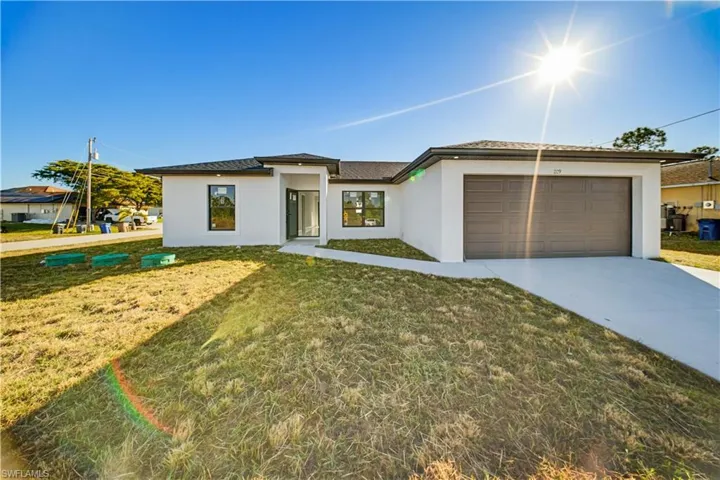 Prairie-style house with a front yard, stucco siding, driveway, and a garage