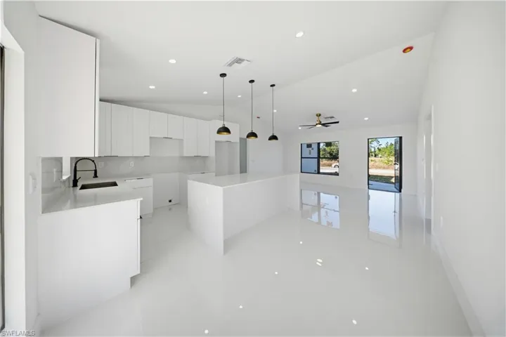 Kitchen featuring a kitchen island, white cabinetry, ceiling fan, hanging light fixtures, and lofted ceiling