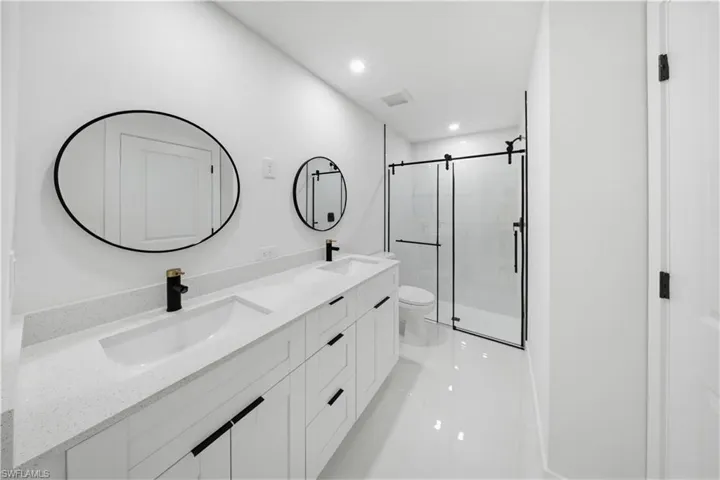 Full bathroom featuring a stall shower, double vanity, and recessed lighting