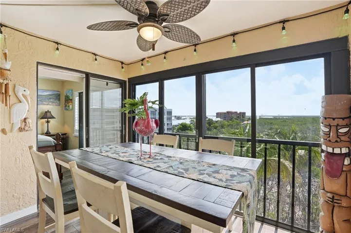 Enclosed balcony featuring expansive windows, a ceiling fan with integrated lighting, and direct access to an interior room through sliding glass doors - Virtually Edited Image
