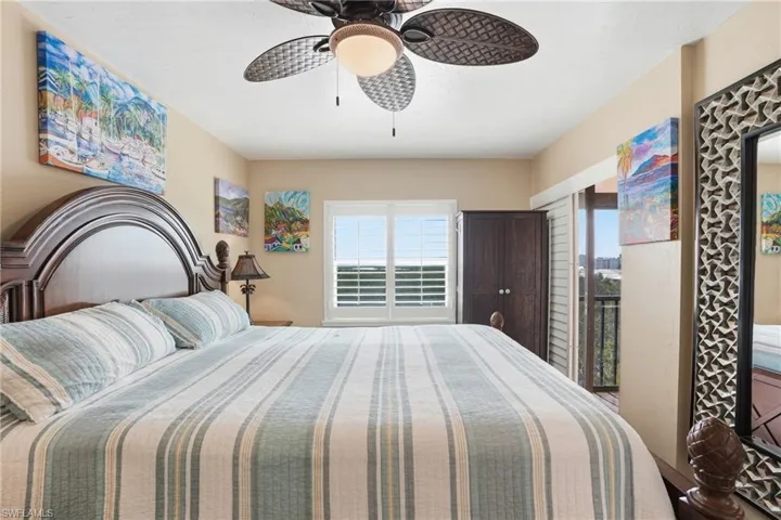 Spacious room featuring a ceiling fan with light fixture, plantation shutters, and access to an exterior balcony - Virtually Edited Image