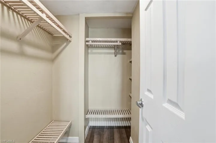 Walk-in closet featuring light wood-finish shelving and hanging rods - Virtually Edited Image