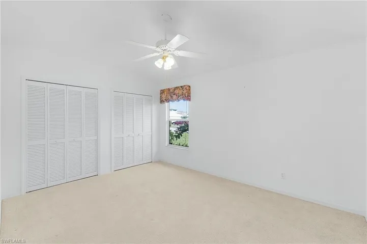 Unfurnished bedroom with two closets, carpet floors, and a ceiling fan