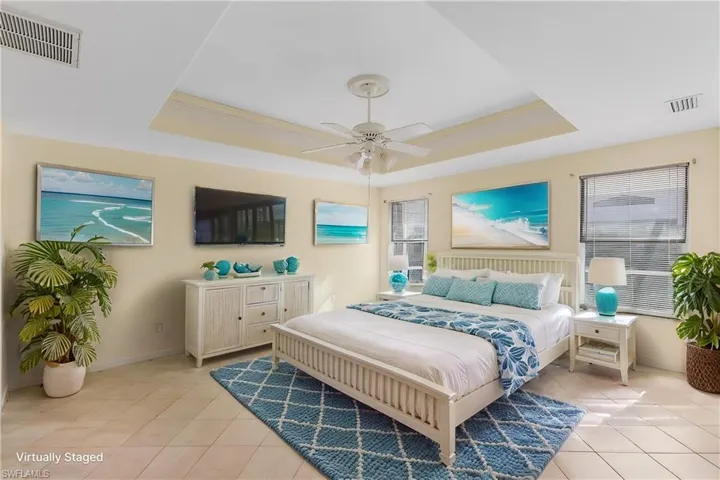 Virtually stagedBedroom featuring a tray ceiling, a ceiling fan, and light tile patterned floors