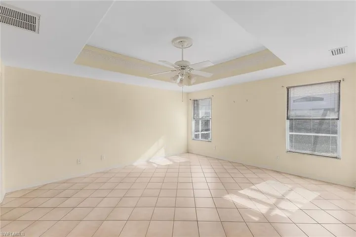 Empty room with a tray ceiling, crown molding, and ceiling fan
