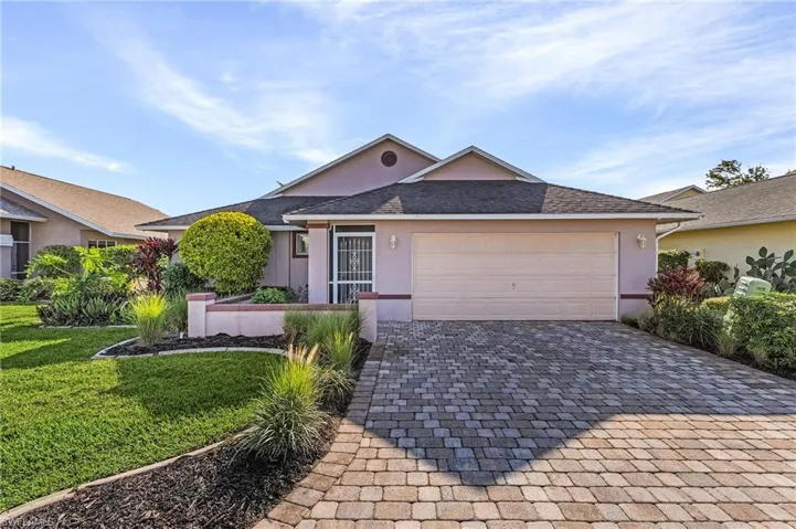 Single story home featuring a garage, stucco siding, decorative driveway, and a front yard