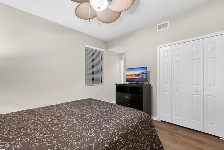 Bedroom with ceiling fan, dark hardwood / wood-style flooring, and a closet