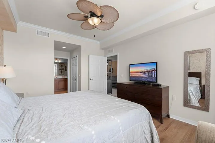 Bedroom with ornamental molding, ceiling fan, hardwood / wood-style flooring, and ensuite bath