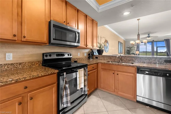 Kitchen featuring stainless steel appliances, sink, dark stone countertops, ceiling fan, and ornamental molding