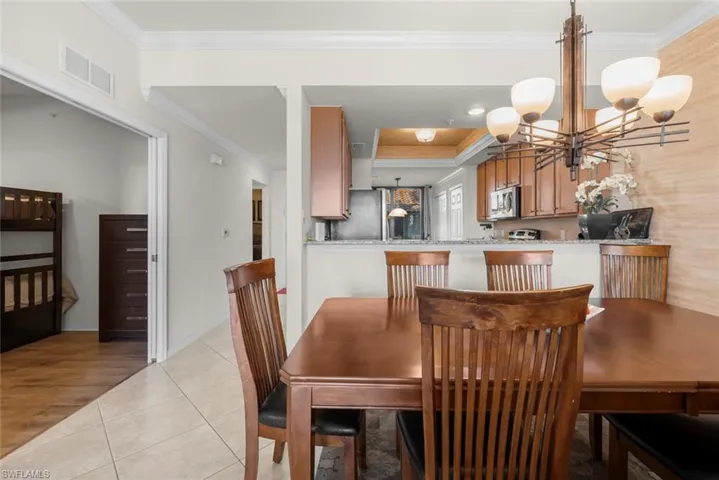 Tiled dining space featuring an inviting chandelier and ornamental molding