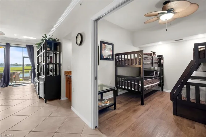 Bedroom with light tile patterned flooring, ornamental molding, and ceiling fan